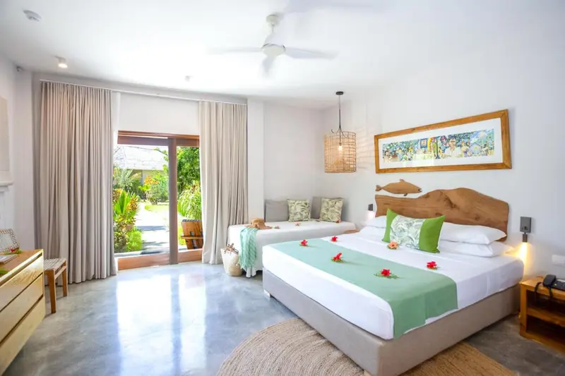 Chambre lumineuse avec un lit double et un canapé près d'une baie vitrée.