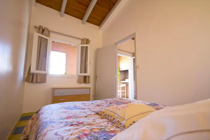 Une chambre lumineuse avec un lit recouvert d'une courtepointe fleurie et une commode.