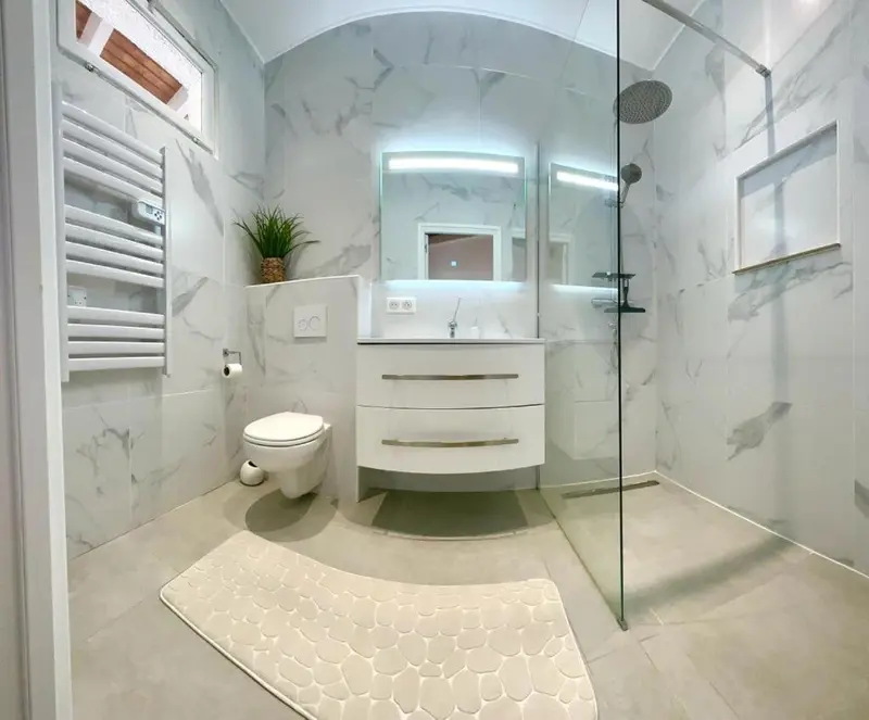 Une salle de bain moderne avec douche à l'italienne et carrelage clair.