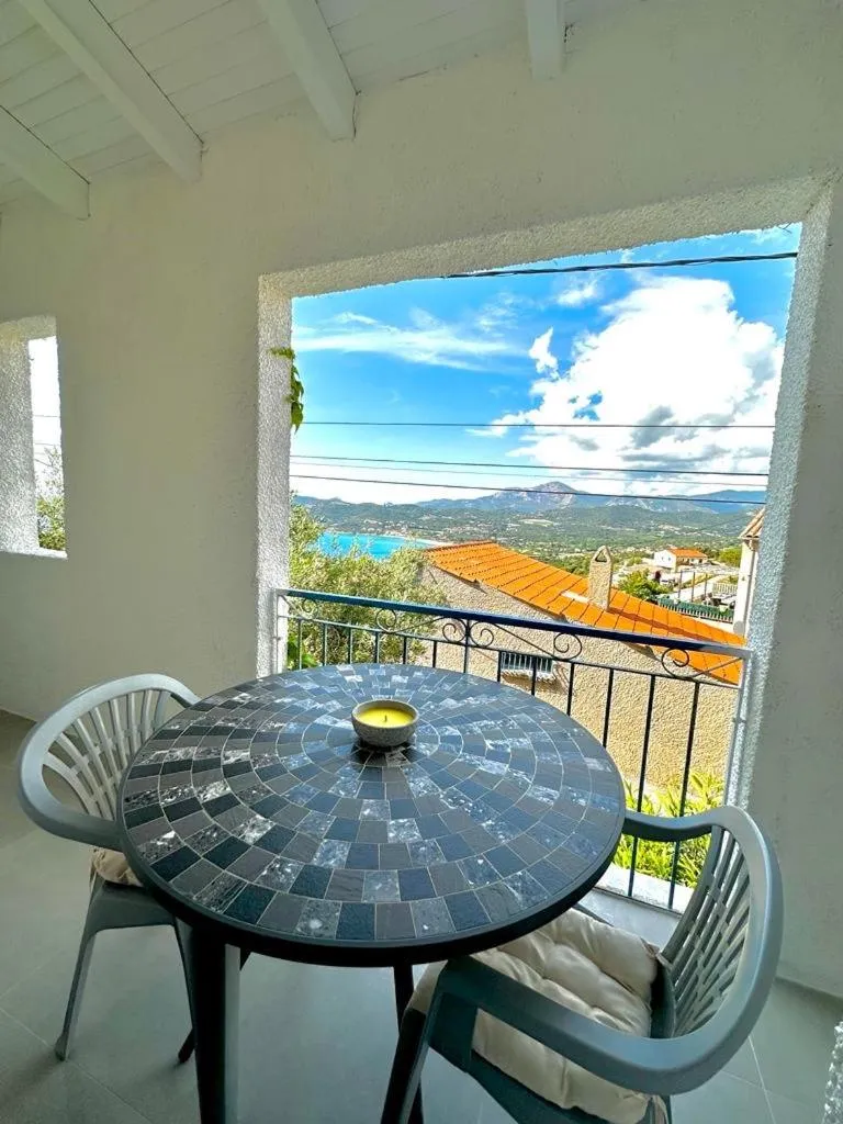 Une table ronde en mosaïque se trouve sur une terrasse avec vue sur la mer et les montagnes.