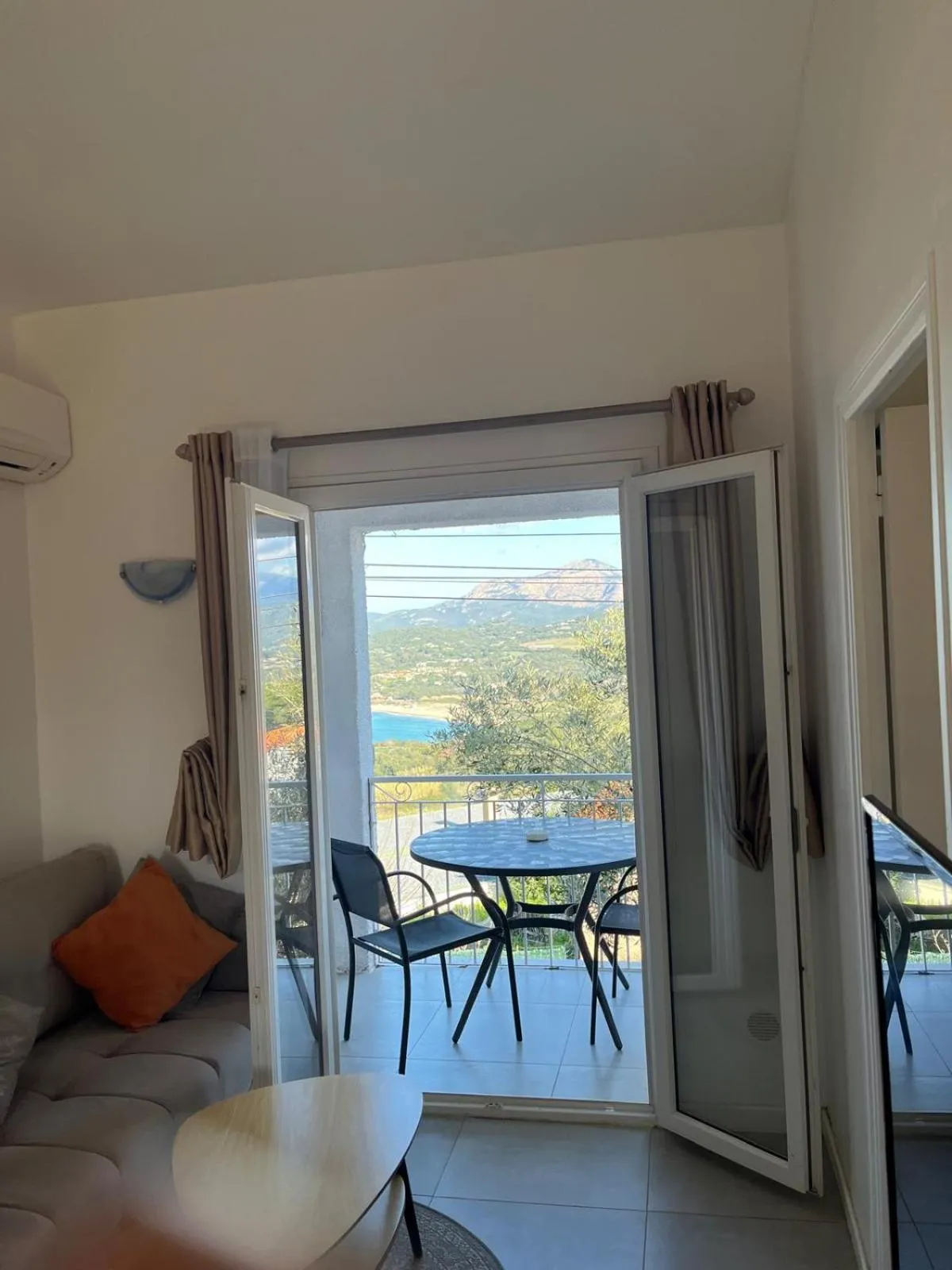 Une pièce de séjour lumineuse s'ouvre sur une terrasse avec vue sur la mer.