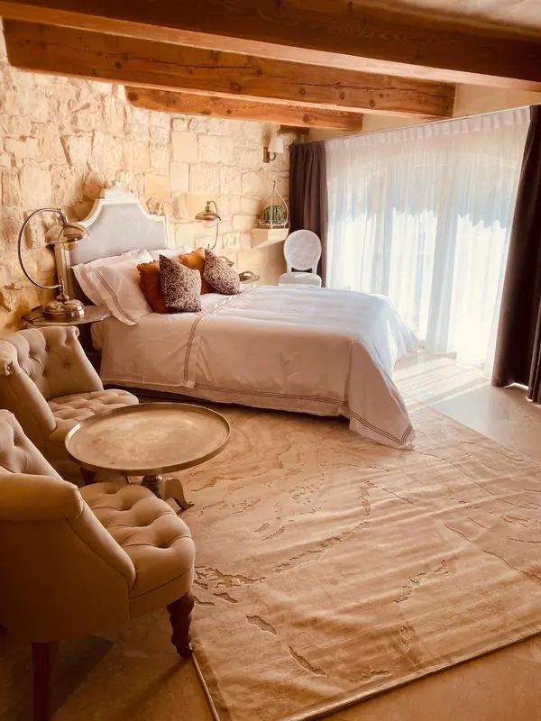 Une chambre lumineuse avec un lit recouvert de linge blanc et un coin salon.