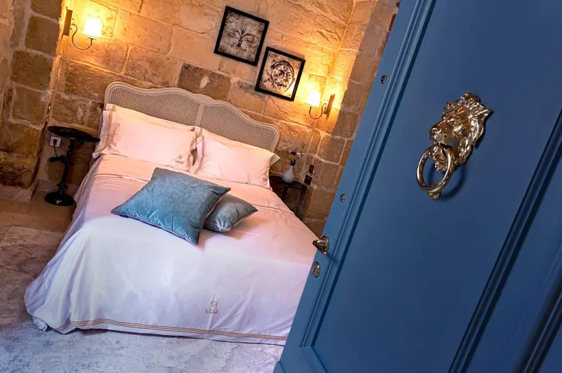 Une chambre à coucher lumineuse avec un lit à baldaquin et des murs en pierre.