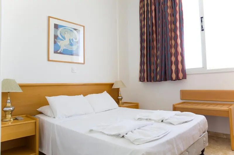 Une chambre lumineuse avec un lit double et des tables de chevet.