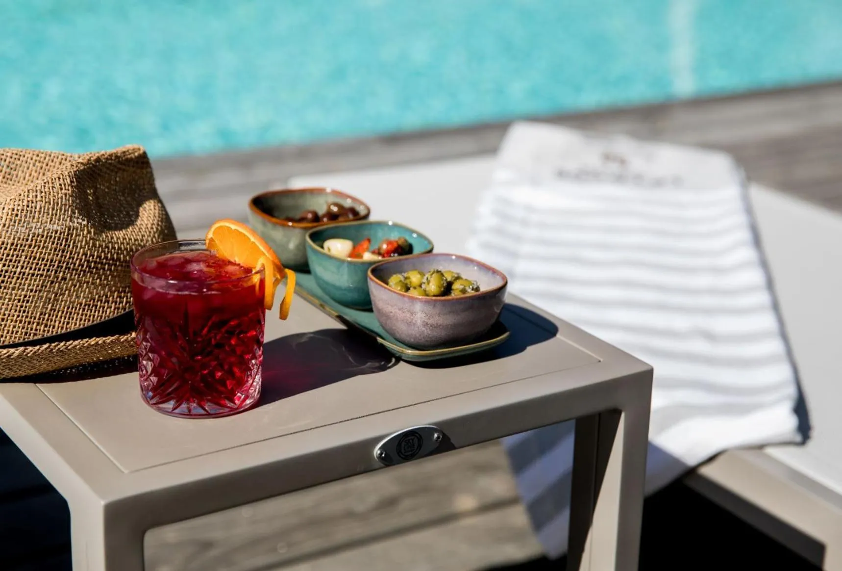 Un cocktail et des amuse-gueules sont servis sur une table près d'une piscine.