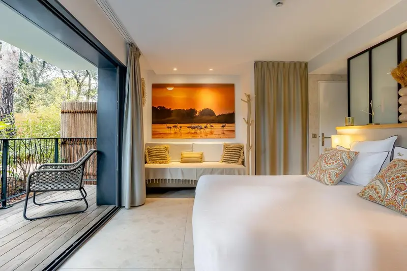 Une chambre lumineuse s'ouvre sur une terrasse avec vue sur la végétation.