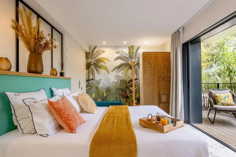 Une chambre lumineuse avec un grand lit recouvert d'une couverture jaune et d'oreillers blancs, donnant sur une terrasse.