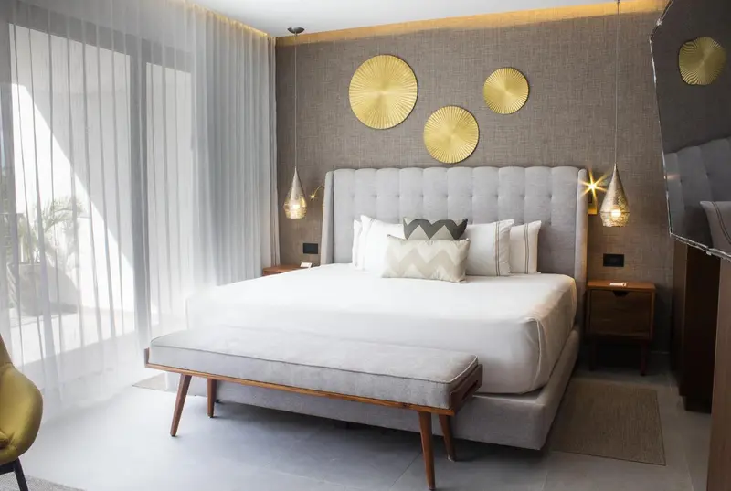 Une chambre lumineuse avec un grand lit et une décoration murale dorée.