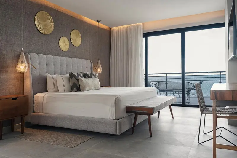 Une chambre avec un grand lit et un accès à un balcon.