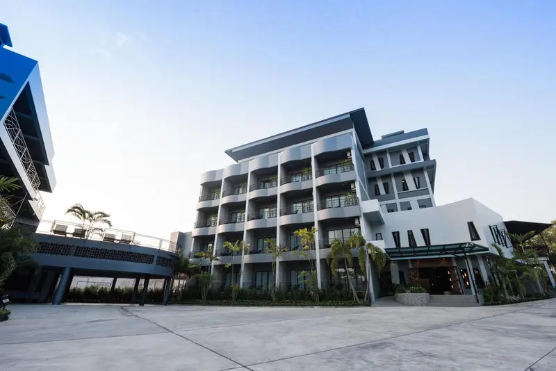Bâtiment moderne à plusieurs étages avec des balcons et une entrée ombragée.
