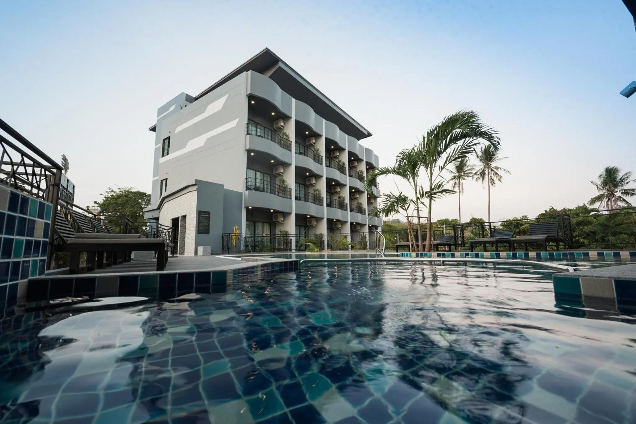 Bâtiment moderne avec piscine et végétation tropicale.