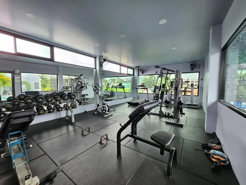 Une salle de sport lumineuse avec des équipements de musculation et des miroirs.