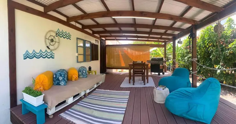 Espace de détente extérieur avec canapés, table à manger et barbecue.