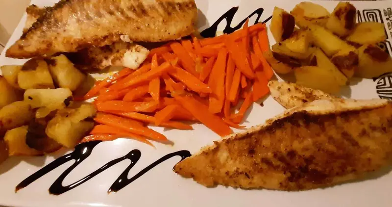 Assiette généreuse composée de poisson grillé, de poulet, de carottes et de pommes de terre.