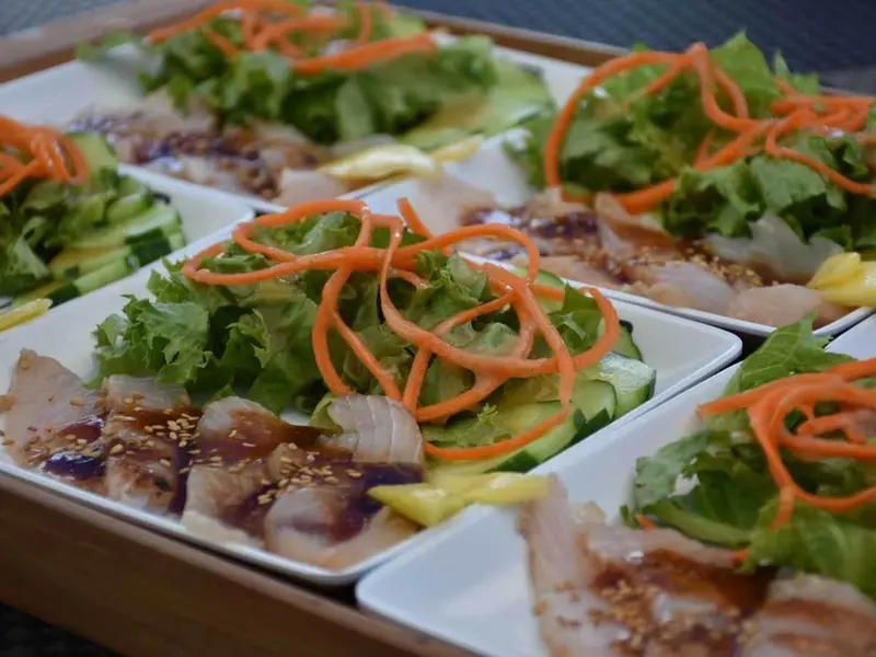 Assiettes de poisson cru garnies de légumes et de sauce.