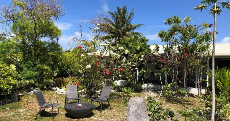 Un jardin luxuriant avec des chaises et un foyer central.