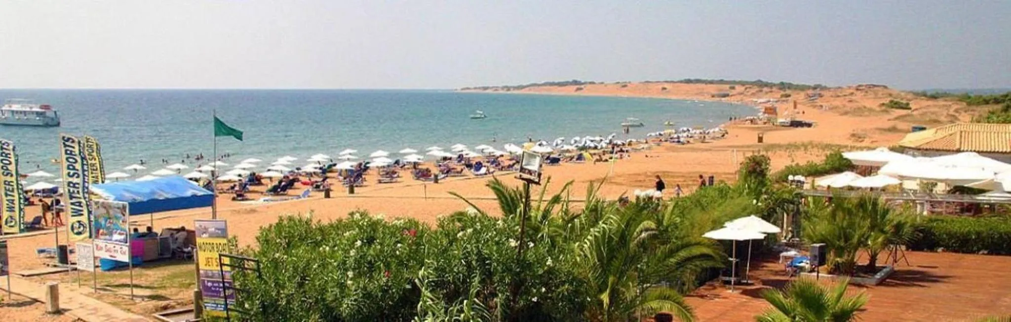 Plage de sable avec transats et parasols face à la mer.