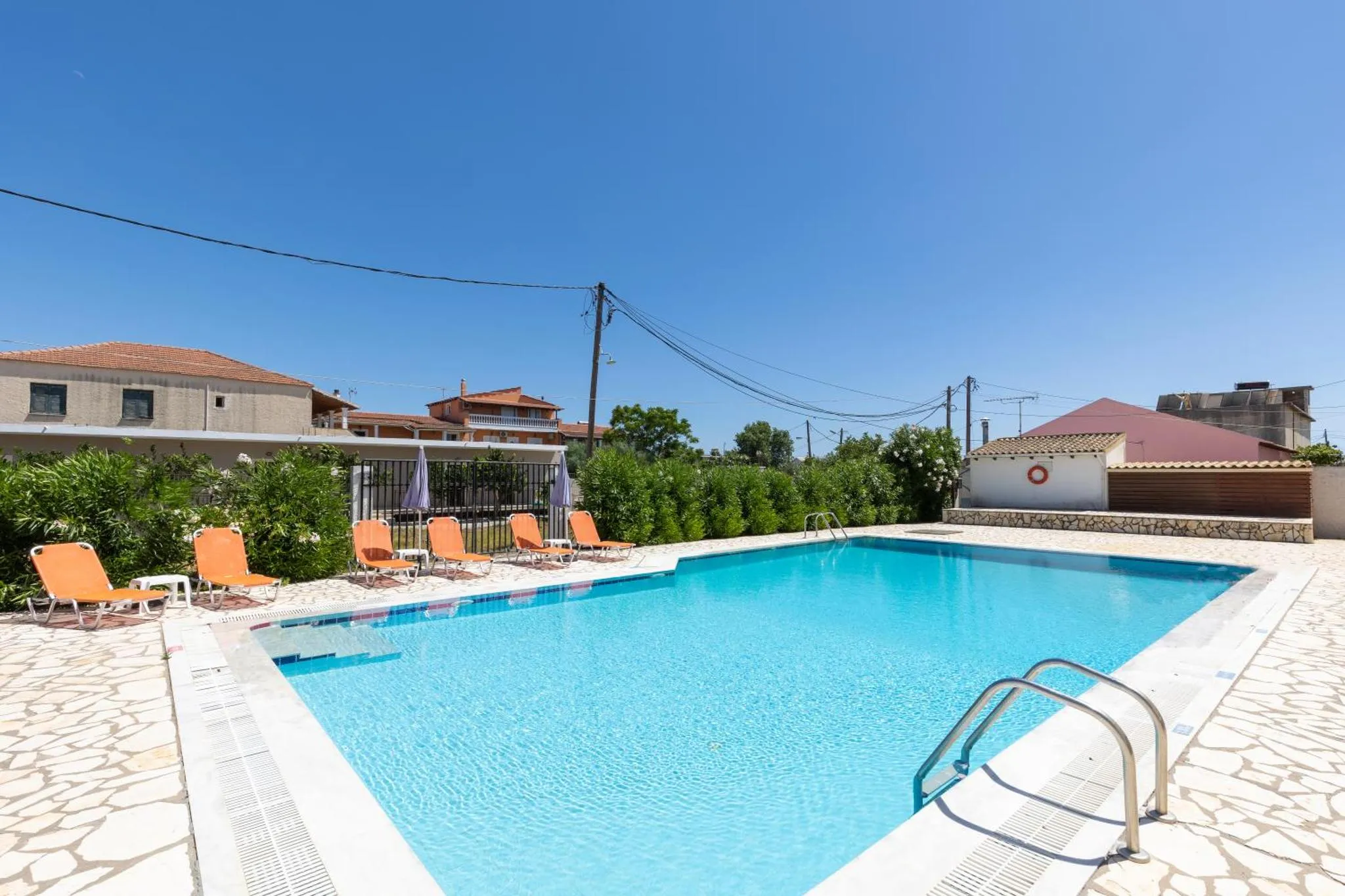 Une piscine rectangulaire bordée de transats sous un ciel bleu dégagé.