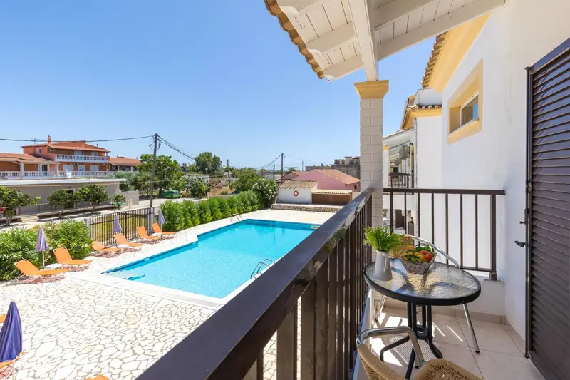 Une terrasse ensoleillée surplombe une piscine et un jardin.