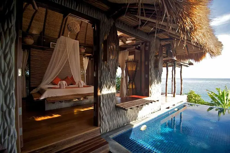 Une chambre avec un lit à baldaquin donnant sur une piscine et la mer.