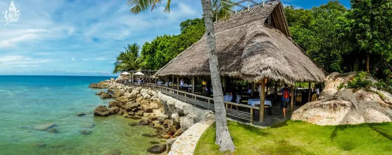 Un restaurant en bord de mer avec une terrasse ombragée.