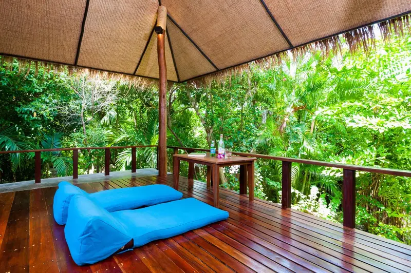 Espace de détente extérieur avec mobilier en bois et coussins bleus.