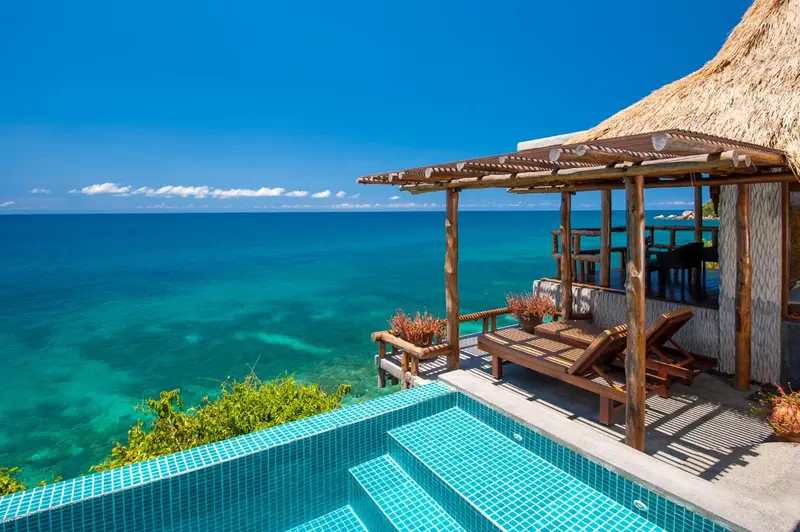 Terrasse avec piscine et vue sur la mer turquoise.