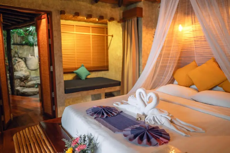Une chambre lumineuse avec un lit décoré de serviettes en forme de cygnes.