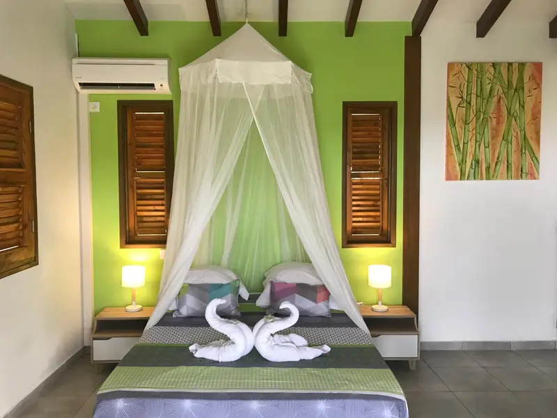 Une chambre lumineuse avec un lit recouvert d'une moustiquaire et décoré de serviettes en forme de cygne.