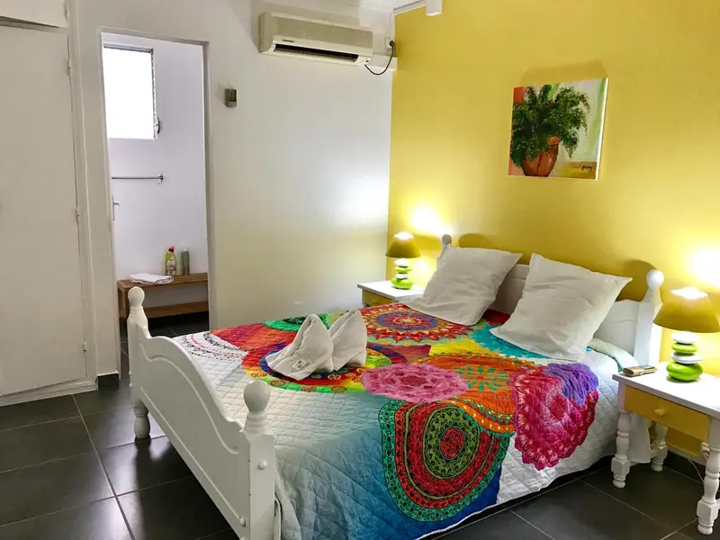 Une chambre lumineuse avec un grand lit recouvert d'une courtepointe colorée.