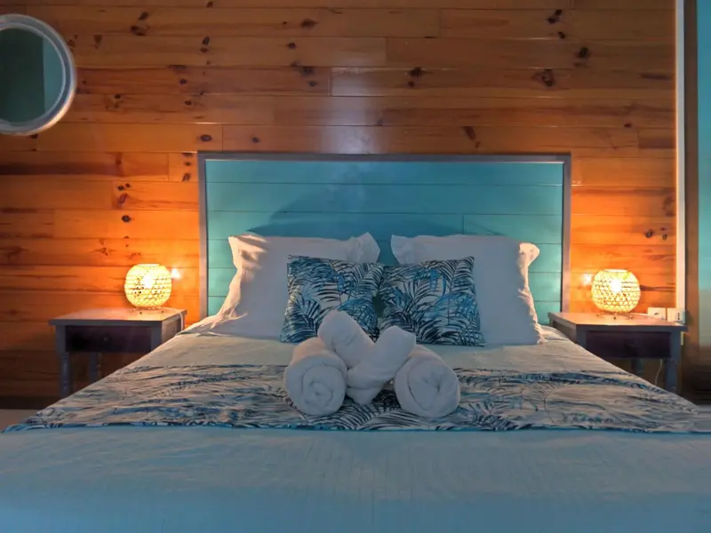Une chambre lumineuse avec un grand lit recouvert d'une courtepointe et de coussins.