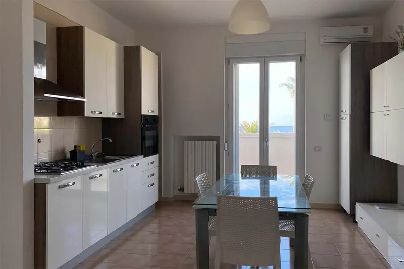 Une cuisine moderne s'ouvre sur une salle à manger avec vue sur la mer.