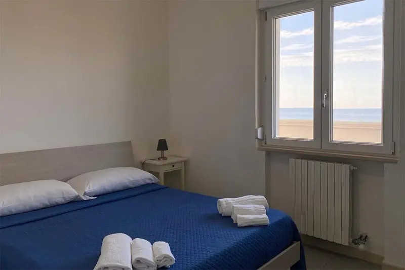 Une chambre lumineuse avec un lit fait et une vue sur la mer.