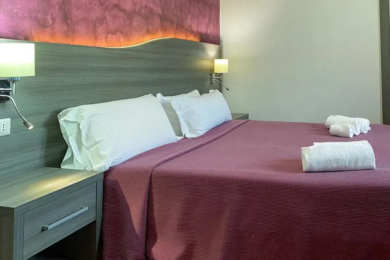 Une chambre avec un grand lit recouvert d'une courtepointe rouge et de coussins blancs.
