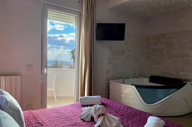 Chambre avec un grand lit et une baignoire d'angle près d'une baie vitrée.