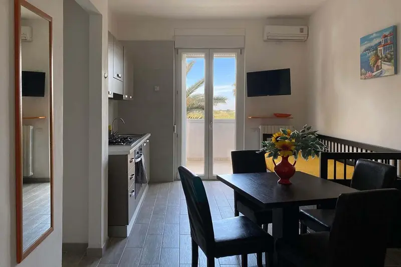 Espace de vie lumineux avec cuisine équipée et table à manger près d'une baie vitrée.