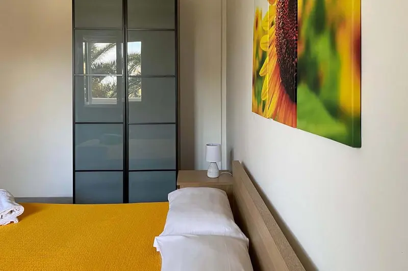 Une chambre lumineuse avec un lit recouvert d'une couverture jaune et une décoration murale colorée.