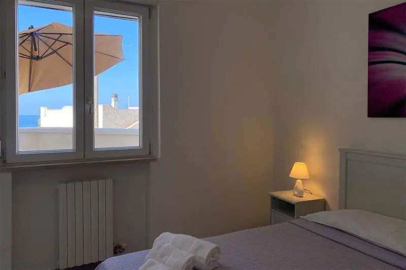 Une chambre lumineuse avec un lit et une vue sur la mer par la fenêtre.