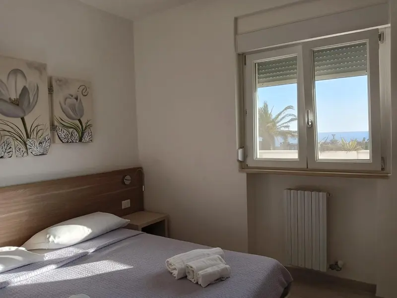 Une chambre lumineuse avec un lit et une vue sur la mer.