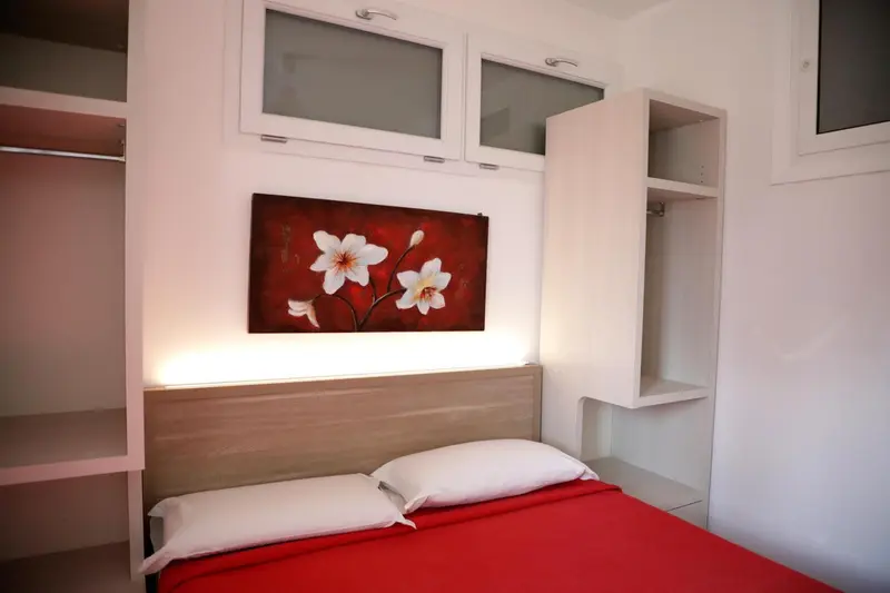 Une chambre avec un lit recouvert d'une courtepointe rouge et une décoration murale florale.