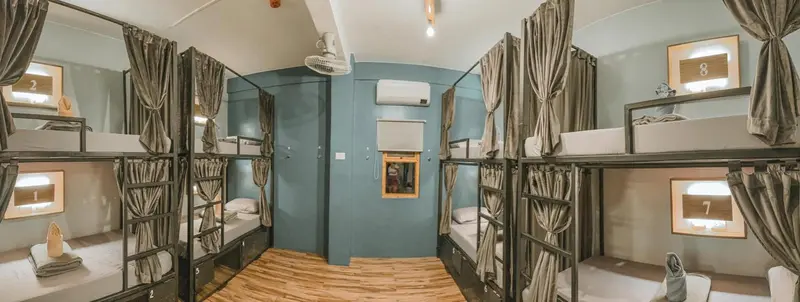 Dortoir avec lits superposés et rideaux de séparation.