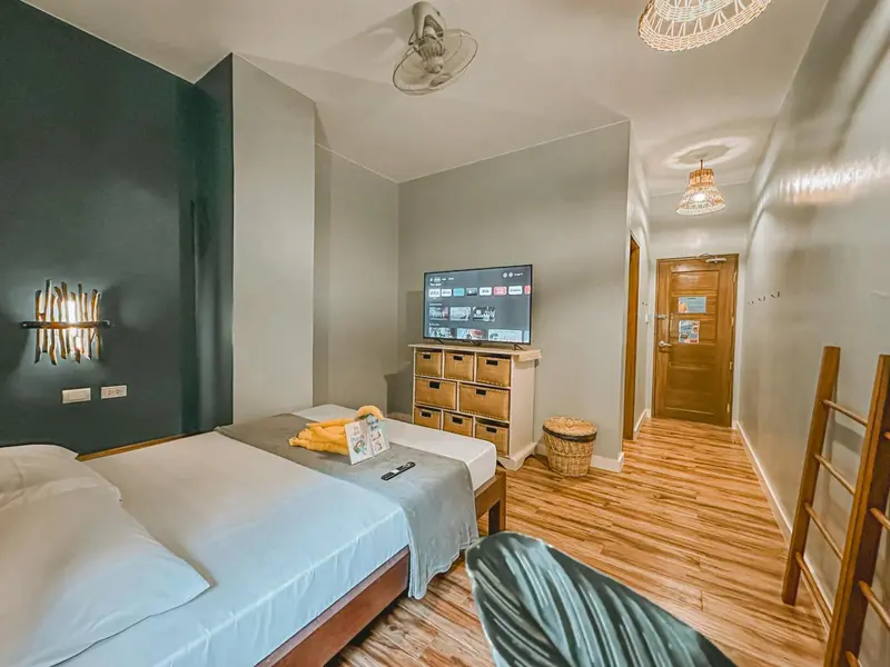 Une chambre lumineuse avec un lit fait et un téléviseur mural.