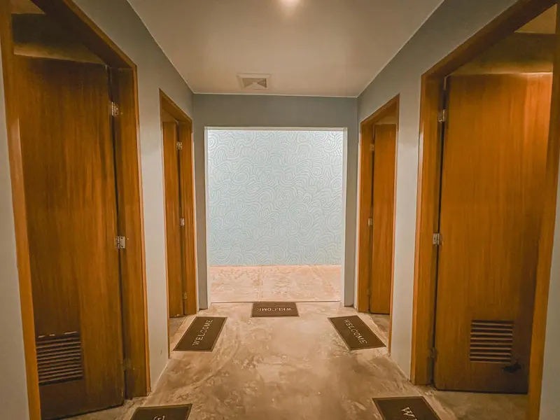 Un couloir d'hôtel mène à plusieurs portes de chambres.