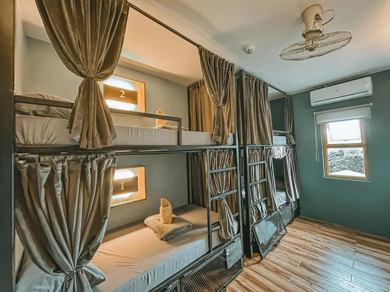 Une chambre avec plusieurs lits superposés et des rideaux de séparation.