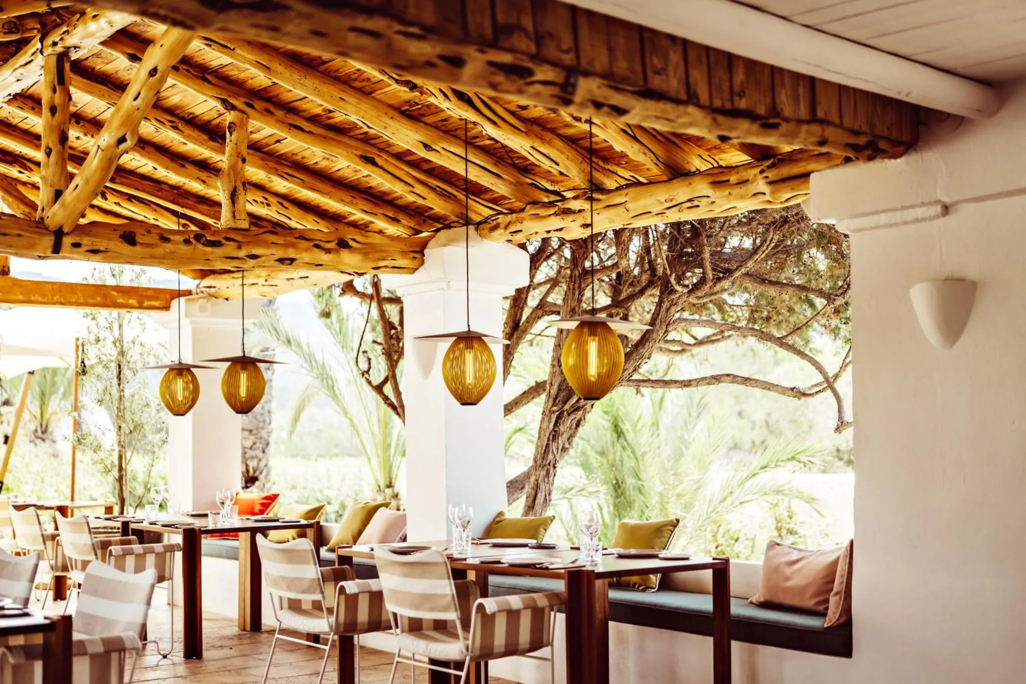 Une salle à manger extérieure ombragée avec des tables et des chaises.