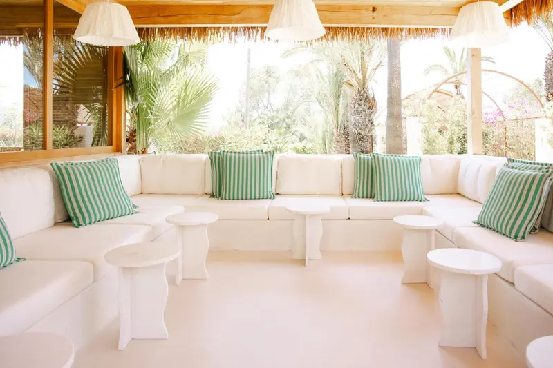 Un espace de détente extérieur avec un canapé blanc et des coussins verts.