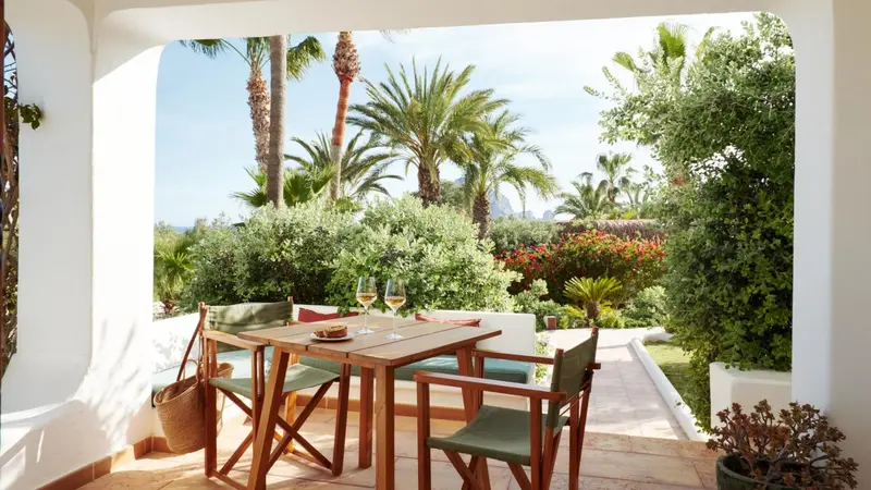 Une table et des chaises en bois invitent à la détente sur une terrasse ombragée.