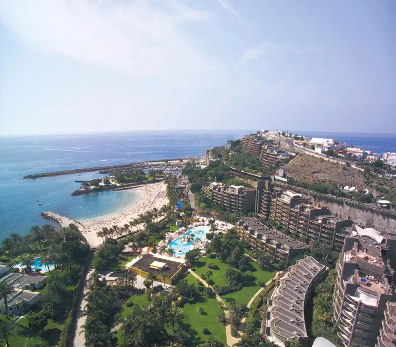 Vue aérienne d'un complexe hôtelier en bord de mer avec piscine et plage.