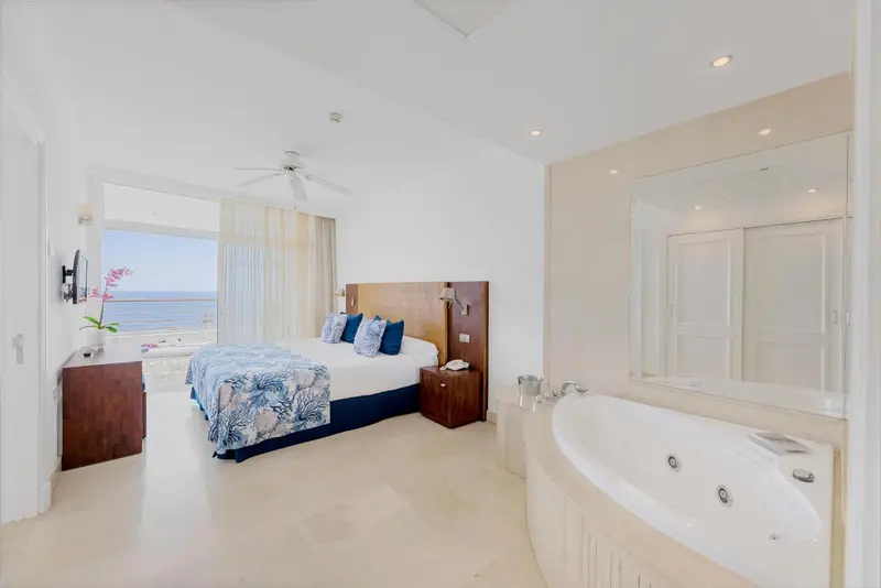 Une chambre lumineuse avec un grand lit et une baignoire îlot.