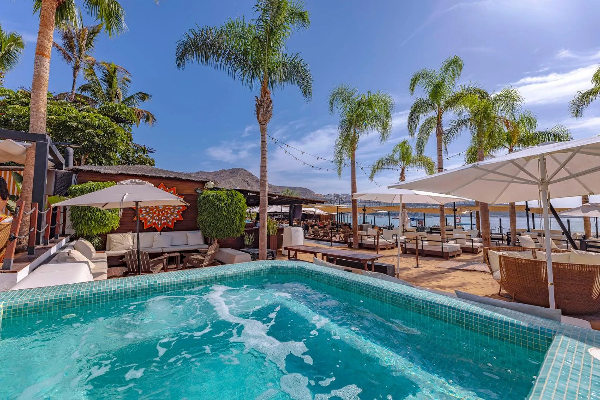 Espace de détente avec piscine et mobilier de jardin face à la mer.